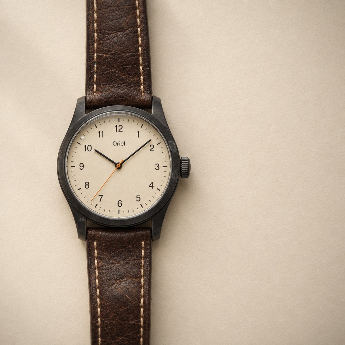 The watch flat on a cream ground with its cream dial seated in the case.