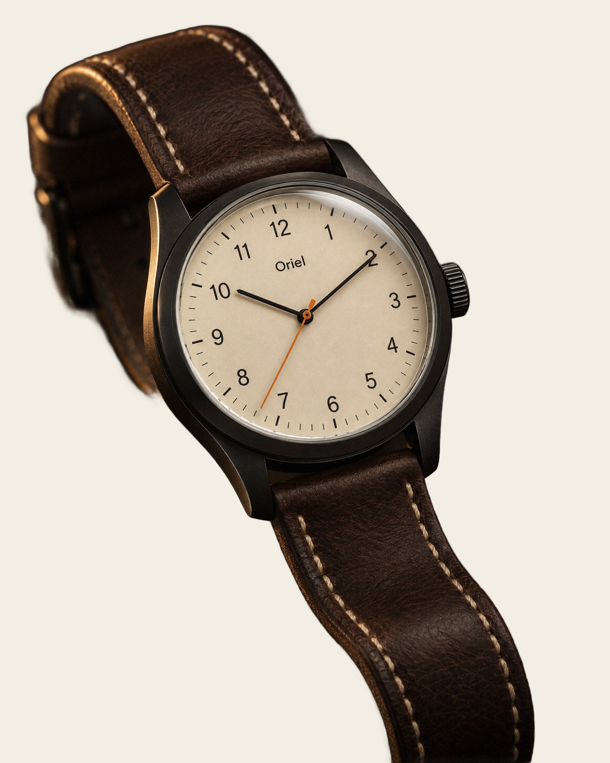 The Oriel Field One: a 38 mm field watch with a cream dial, a dark case and a brown leather strap.